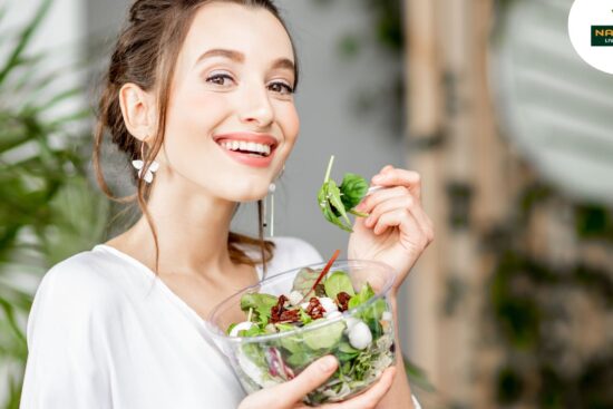 A smiling woman presents a vibrant salad, emphasizing freshness and enjoyment in healthy eating.