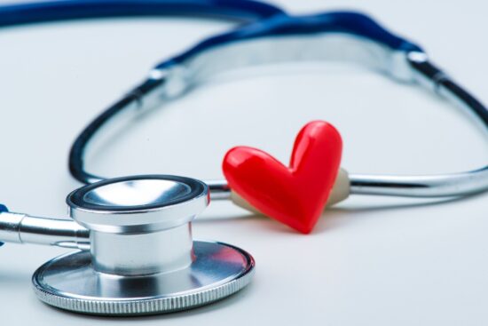 A stethoscope and a red heart-shaped object on a white surface.