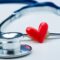 A stethoscope and a red heart-shaped object on a white surface.