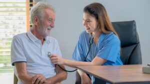 A nurse checks the heart of an elderly man using a stethoscope, demonstrating care and professionalism.